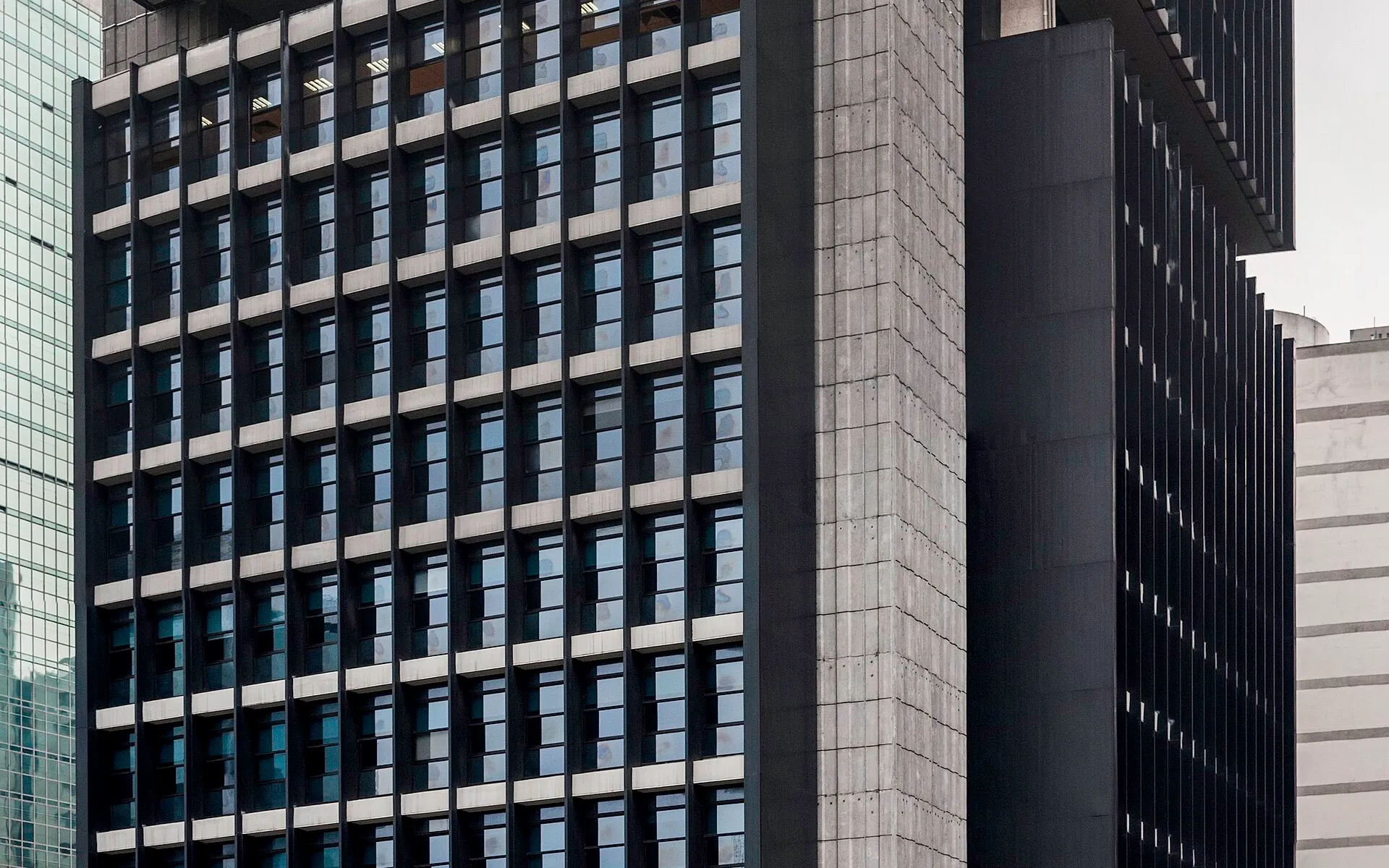 Detalhe da fachada de grade escura e concreto de uma torre do Banco Central do Brasil, na Avenida Paulista, em São Paulo.