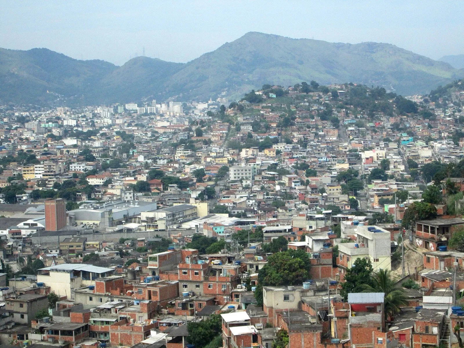 Vista aérea do Complexo do Alemão, com casas densamente ocupadas e montanhas ao fundo.