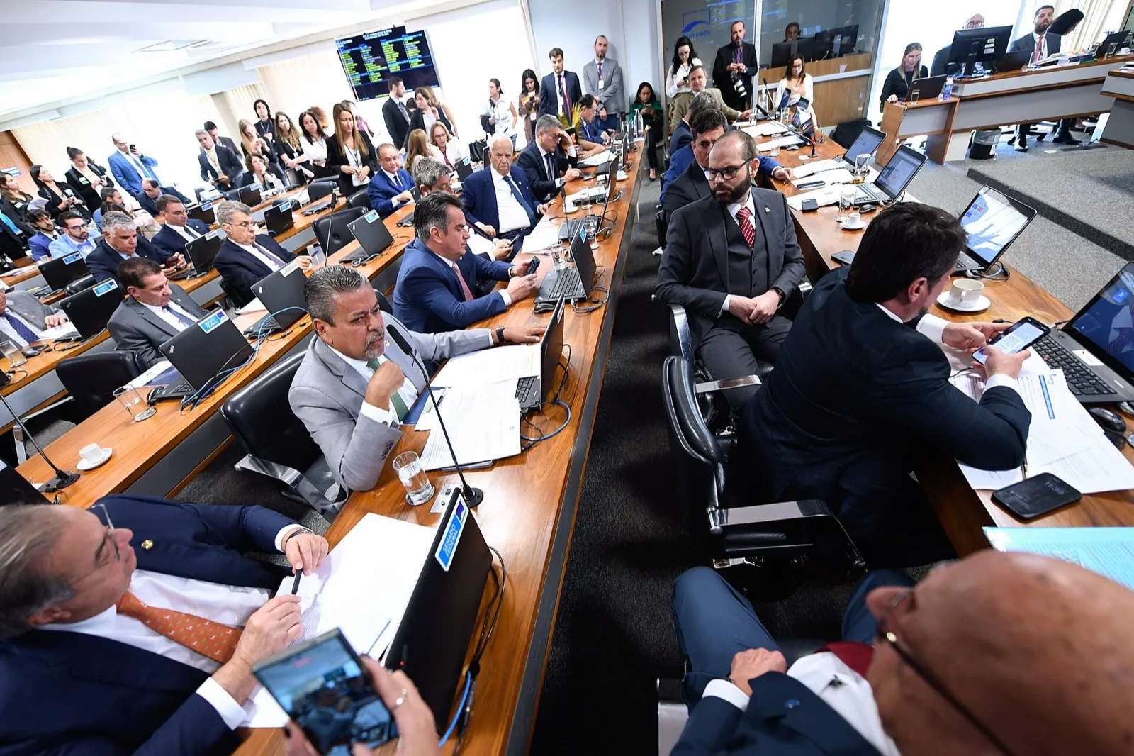 Senadores reunidos em torno de uma mesa em forma de U durante sessão da Comissão de Constituição e Justiça, com computadores e microfones.